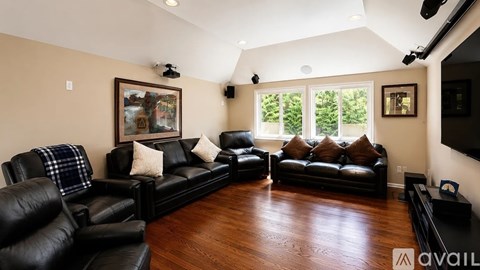 A living room with black leather furniture and a painting on the wall.