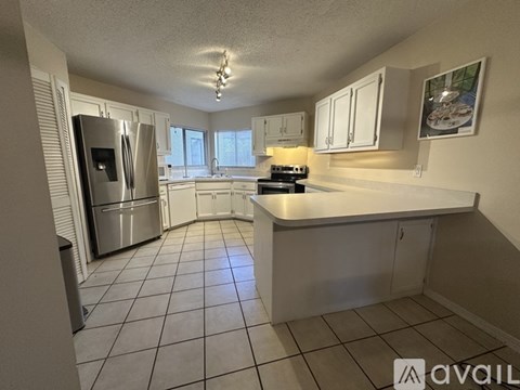 A kitchen with white cabinets and a stainless steel refrigerator.
