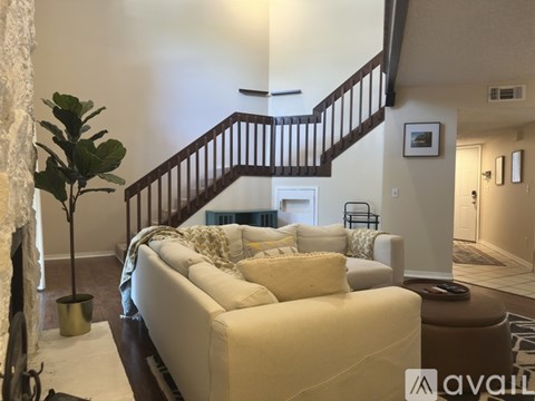 A living room with a white couch and a staircase.