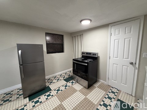 A kitchen with a fridge, oven and a tiled floor.