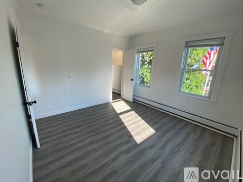 A room with a grey floor and a window with an American flag on it.
