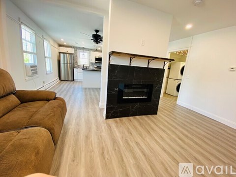 A modern living room with a fireplace and a kitchen in the background.