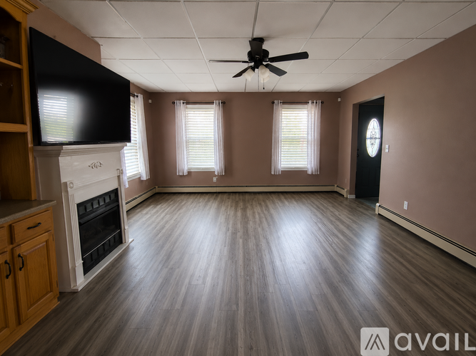 A spacious room with wood flooring and a ceiling fan.