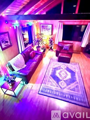 A living room with a couch, a rug, and a table with a vase on it.