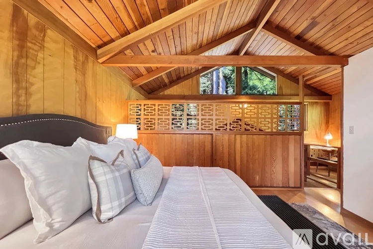 A bedroom with a bed, pillows, and a wooden ceiling.