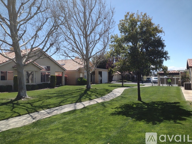 A grassy area with trees and houses in the background.