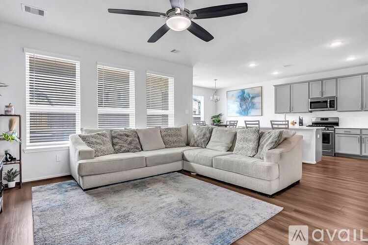A spacious living room with a large sectional sofa and a ceiling fan.