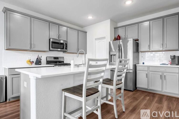 A kitchen with white cabinets and a white island with a sink.