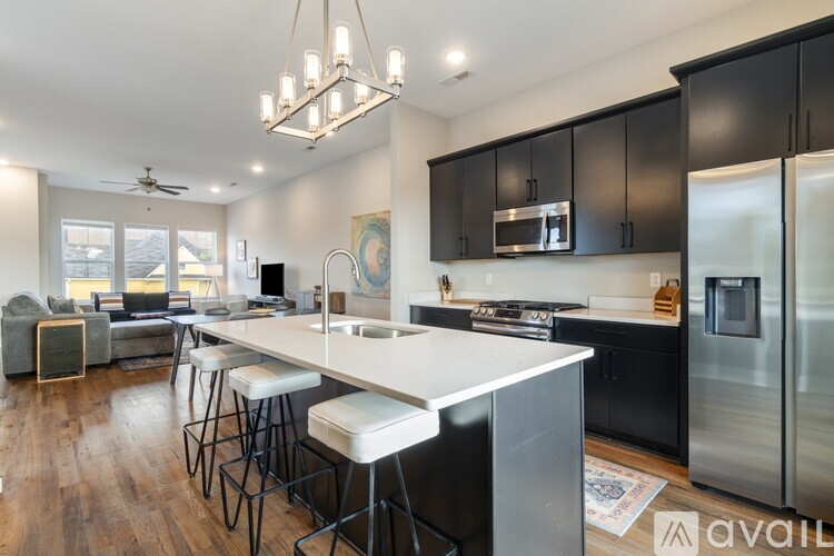 A modern kitchen with a white island and black cabinets.