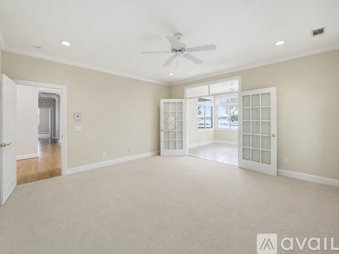 A spacious room with a ceiling fan and carpeted floor.