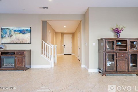 A spacious living room with a television, a cabinet, and a painting on the wall.