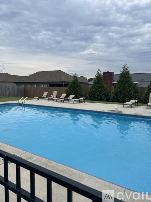 A pool with chairs around it and a cloudy sky.