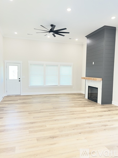 A spacious room with a fireplace and a ceiling fan.