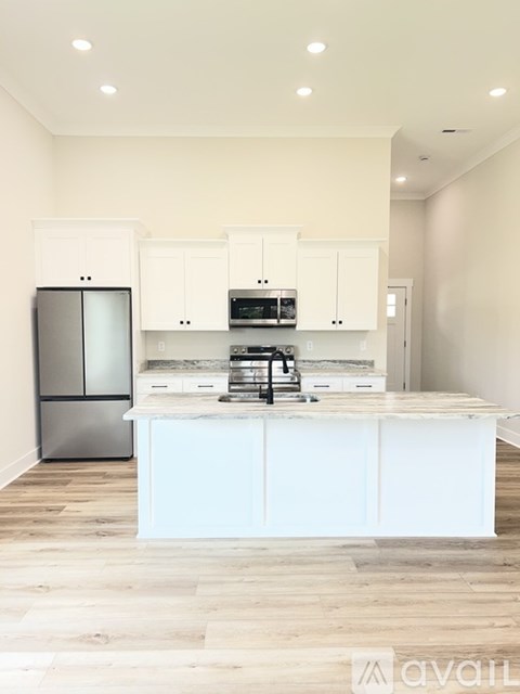 A kitchen with white cabinets and a wooden island.