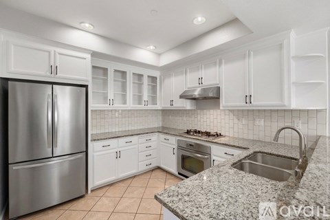 A kitchen with white cabinets and a granite countertop.