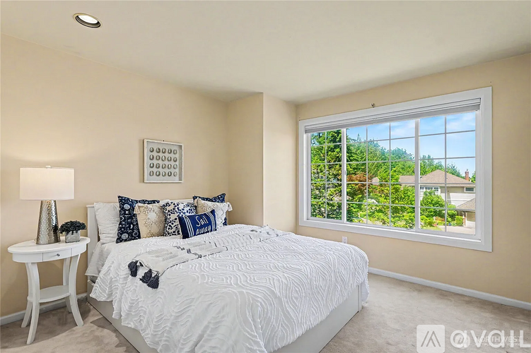 A bedroom with a large bed and a window overlooking a green area.