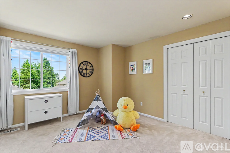 A room with a teepee, a yellow duck toy, and a white dresser with a window overlooking trees.