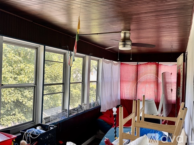 A room with a ceiling fan and a window overlooking trees.