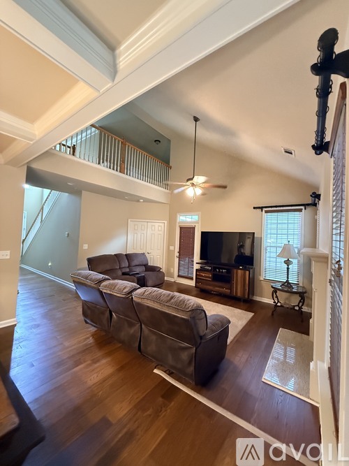 A living room with a brown leather couch and a wooden floor.