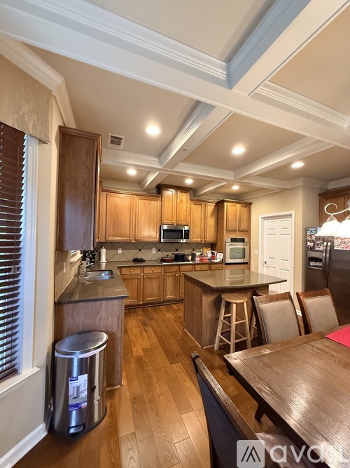 A kitchen with wooden cabinets and a stainless steel trash can.