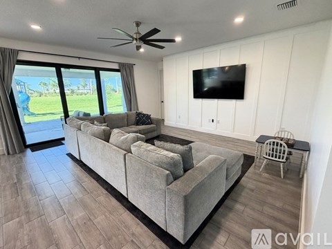 A living room with a grey sofa and a television mounted on the wall.