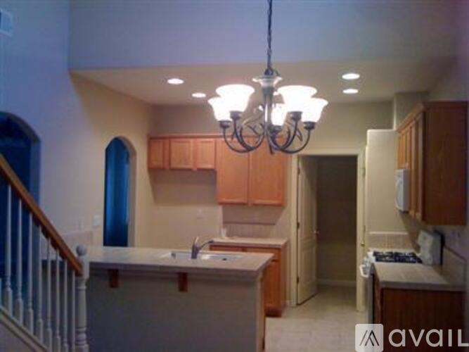 A kitchen with wooden cabinets and a chandelier hanging from the ceiling.