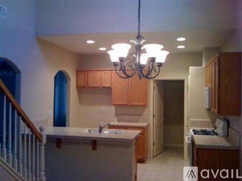 A kitchen with wooden cabinets and a chandelier hanging from the ceiling.