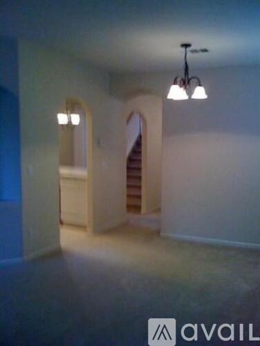 A room with a chandelier and a staircase.