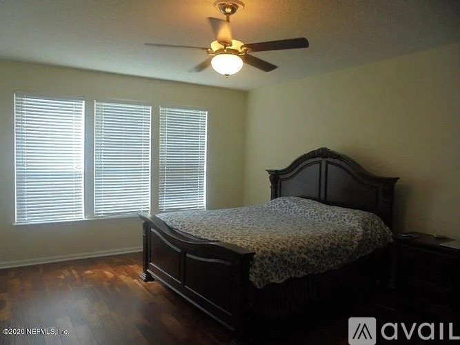 A bedroom with a bed, a ceiling fan, and a window with blinds.