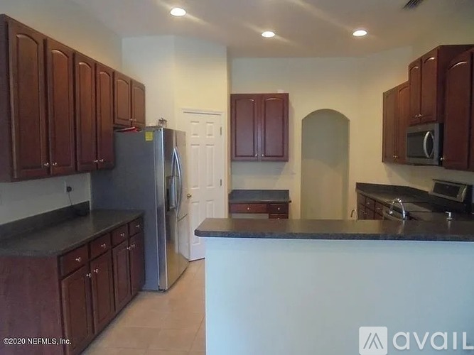 A kitchen with brown cabinets and a black countertop.