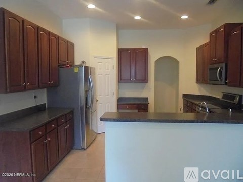 A kitchen with brown cabinets and a black countertop.