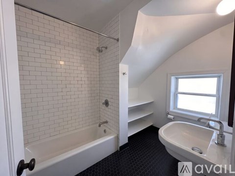 A white bathroom with a bathtub, sink, and window.