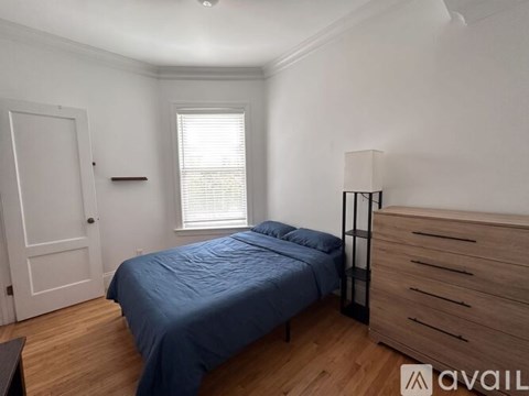 A bedroom with a bed, dresser, and window.