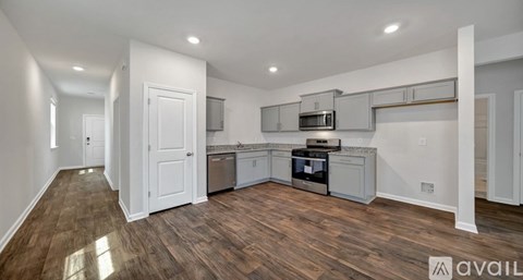 A kitchen with white cabinets and a wooden floor.