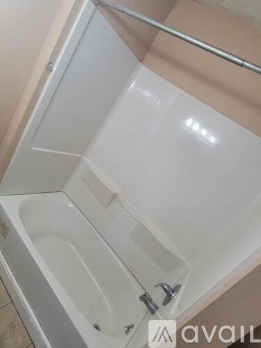 A white bathtub with a shower head and faucet.