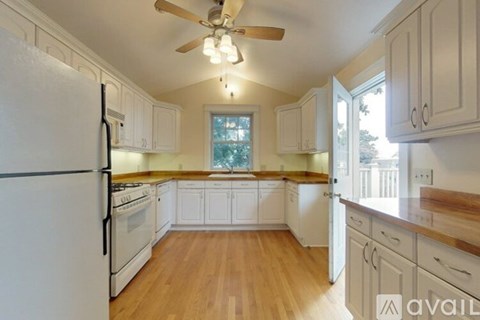 A kitchen with white cabinets and a wooden floor.