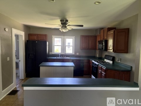 A kitchen with a black refrigerator and wooden cabinets.