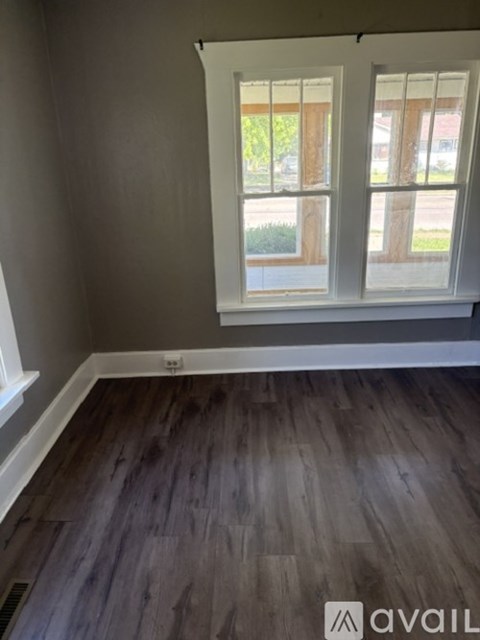 A room with a window and wooden flooring.