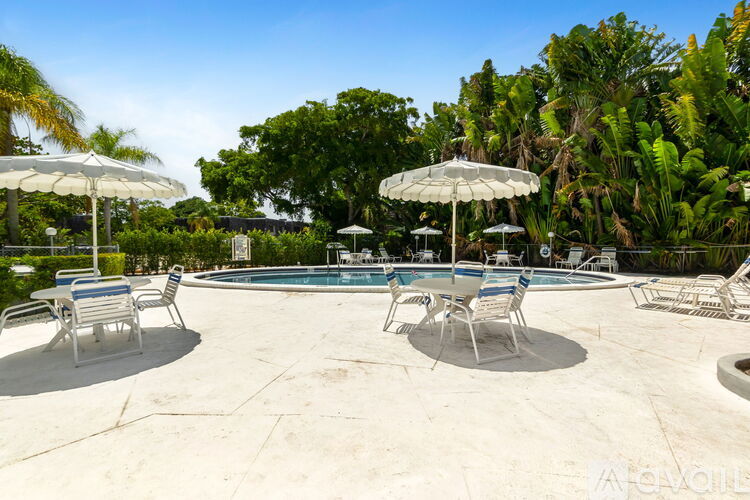 A pool area with chairs and umbrellas surrounded by greenery.