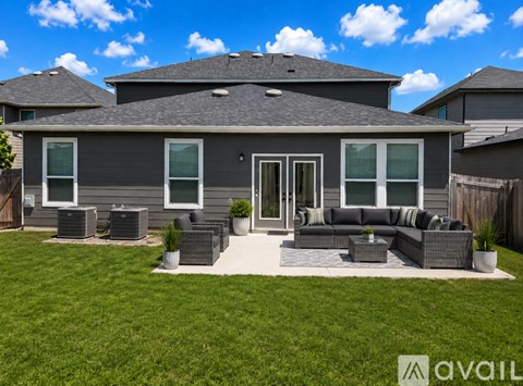 A house with a grey roof and a patio with a sofa and chairs.