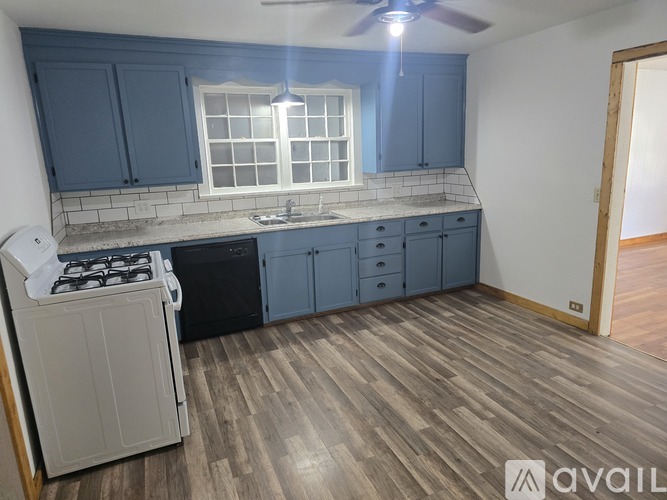 A kitchen with a white stove top oven and blue cabinets.