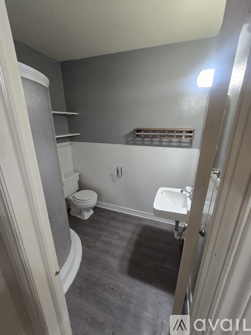 A bathroom with a toilet, sink, and shelves.