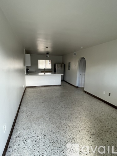 A spacious room with a speckled floor and white walls.