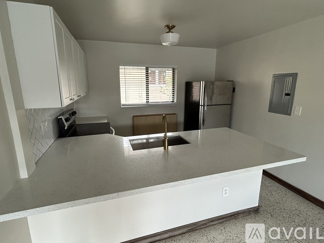 A kitchen with white cabinets and a stainless steel refrigerator.