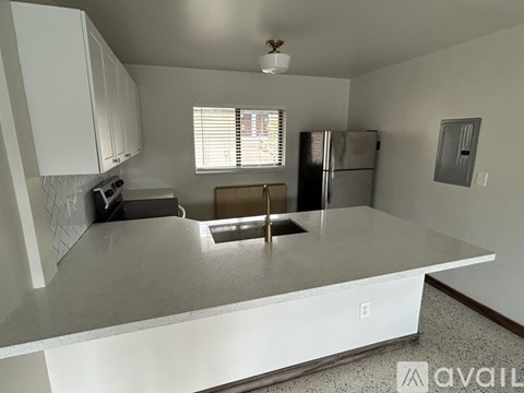 A kitchen with white cabinets and a stainless steel refrigerator.