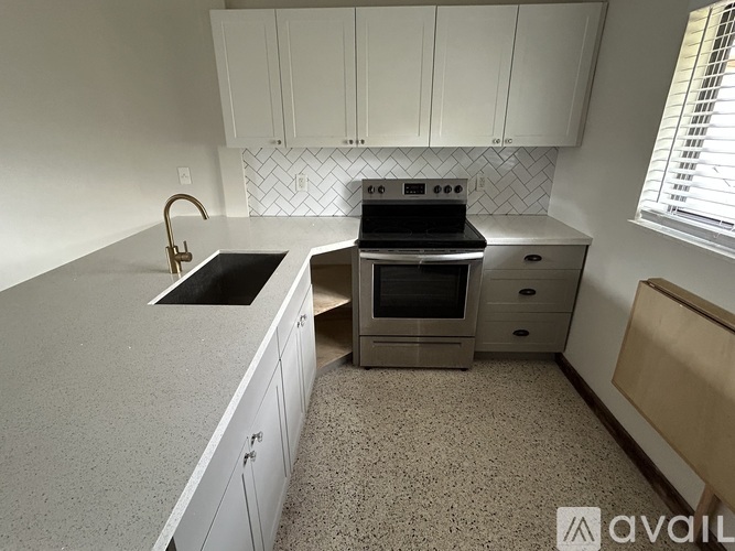 A kitchen with a sink, stove, and cabinets.