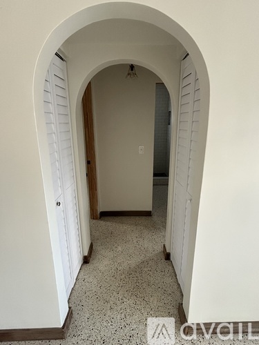 A hallway with a white arched doorway and a tiled floor.