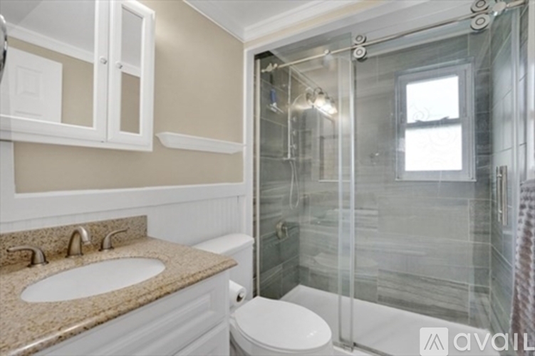 A bathroom with a glass shower stall and a toilet.