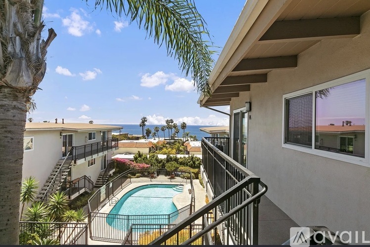 A balcony with a pool and palm trees.