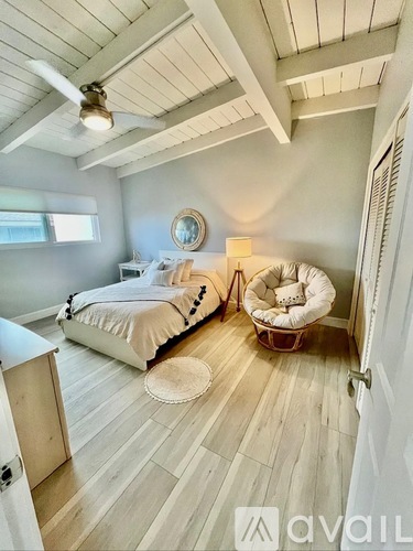 A bedroom with a bed, a chair, and a ceiling fan.